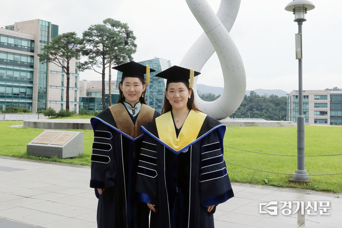 가천대에서 나란히 박사학위를 받은 중국인 쌍둥이 유학생 유하이징(사진 왼쪽, 언니), 유하이닝(사진 오른쪽, 동생)이 대학 가천관 잔디광장에서 학위복을 입고 기념사진을 촬영하고 있다. (사진=가천대학교 제공)