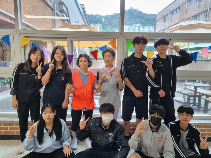  권금숙 미화원과 김순자 미화원이 매홀중학교 학생들과 사진을 찍고 있다. (사진=매홀중학교 제공)