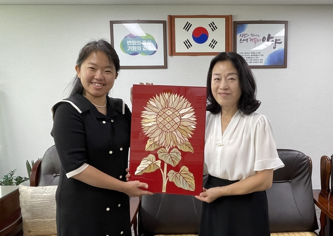 맥간아트 이은지 대표(왼쪽)가 지난 22일 평촌동 행정복지센터를 찾아 박서진 평촌동장에서 맥간공예 작품을 기증하고 있다.(사진=안양시 제공)