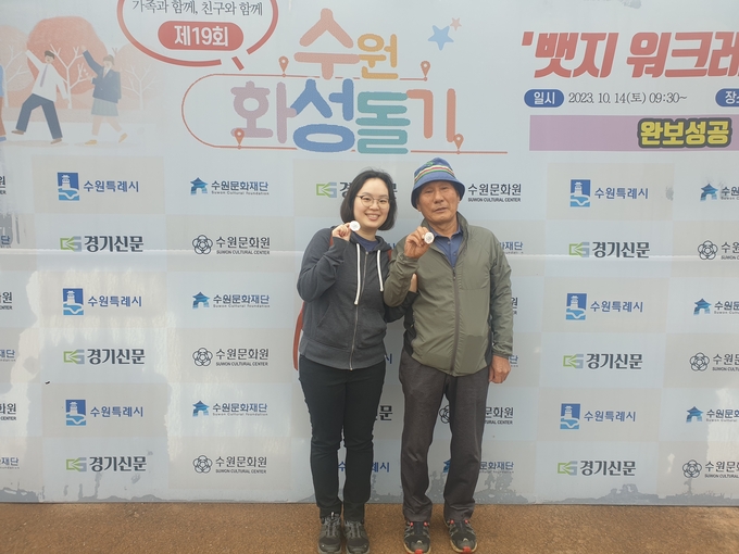 14일 오전 수원 화성행궁 광장에서 열린 ‘2023 제19회 수원화성돌기 시즌2 뱃지 워크레이스’에서 이재호(오른쪽), 이주연 부녀가 완주 배지를 들고 기념 촬영을 하고 있다. (사진=경기신문)