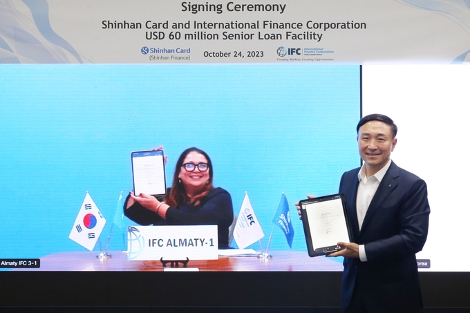 모미나 아이자주딘(Momina Aijazuddin) IFC MCT 금융기관그룹 담당 수석대표(왼쪽)와 문동권 신한카드 사장(오른쪽)이 비대면 랜선방식 투자 유치 조인식에서 기념촬영을 하고 있다. (사진=신한카드 제공)