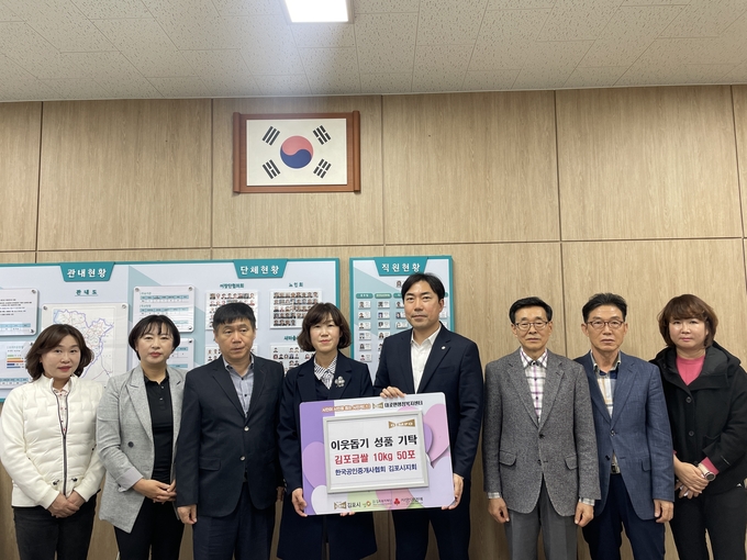 한국공인중개사협회 김동신 김포시지회장(오른쪽 4번째)이 대곶면 김순애 면장에게 "어려운 이웃에게 전해달라"며 백미 50포를 기탁하고 있다. (사진=대곶면사무소 제공)