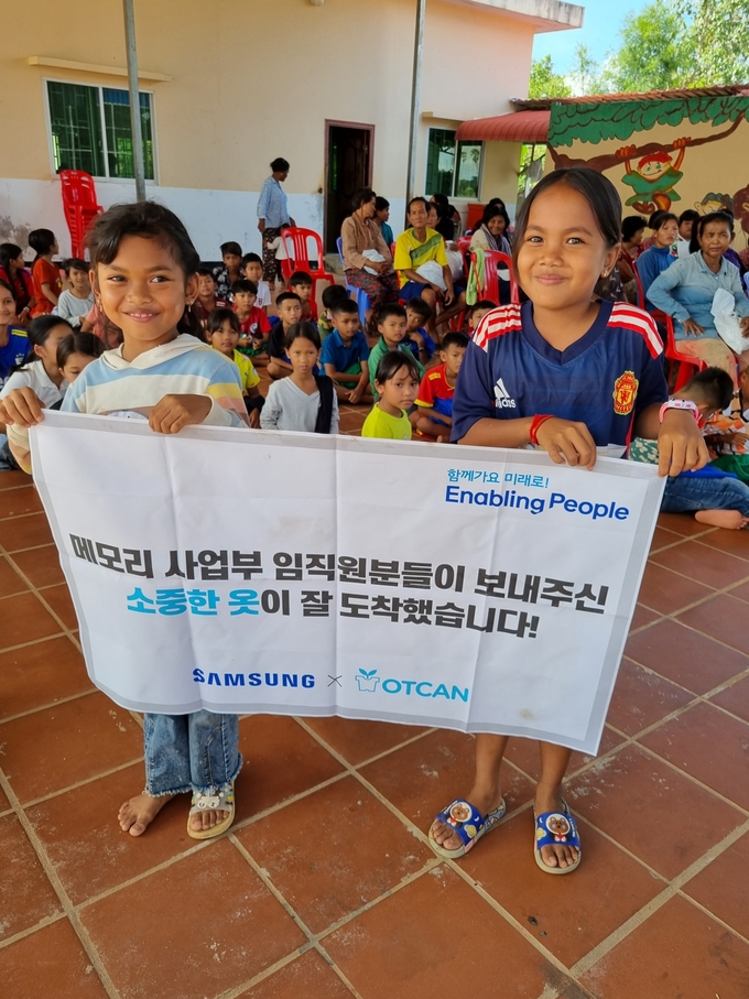 삼성전자 메모리사업부 임직원들의 옷기부를 받은 캄보디아의 아이들이 환하게 웃고 있다. (사진=삼성전자 제공)