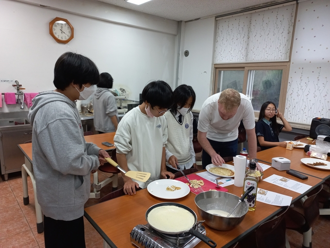  흥천중 원어민 강사인 토마스 교사가 학생들과 함께 해외 요리를 준비하는 모습. (사진=흥천중 제공)