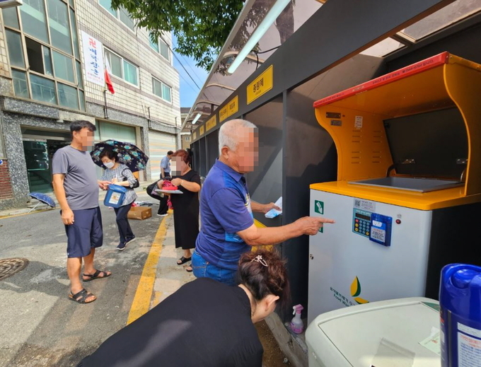 지동 주민들이 마을만들기 사업으로 마련된 에코스테이션과 음식물 폐기물 RFID 기기를 이용하고 있다. (사진=수원시 제공)