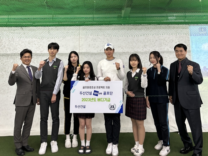 오세욱 두산건설 상무(왼쪽 첫번째)와 김민솔 두산건설 We’ve 골프단 선수(왼쪽 다섯번째), 김팔성 강북중학교 교장(왼쪽 여덟번째)를 비롯해 강북중학교 학생들이 기념사진을 찍고 있는 모습. (사진=두산건설 제공)