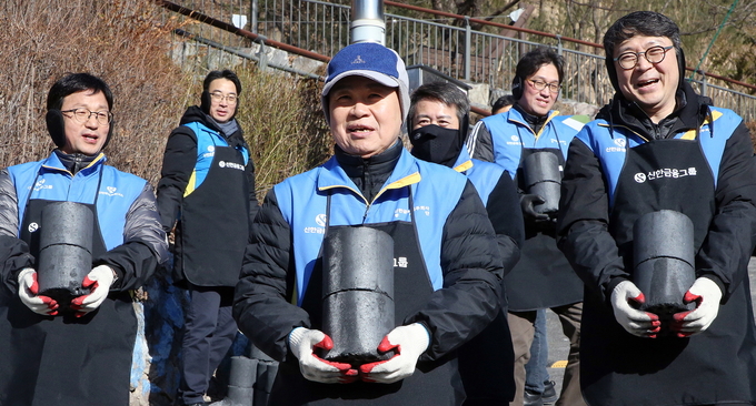 진옥동 신한금융그룹 회장(가운데)이 정지호 신한파트너스 사장(왼쪽), 이동현 신한벤처투자 사장(오른쪽)을 비롯한 임직원 봉사자들과 연탄을 나르고 있다.