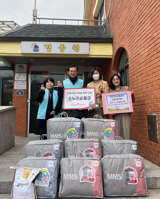 원광연 국민건강보험공단 수원서부지사장(왼쪽 두 번째)이 사회복지법인 경동원에 온누리상품권 및 이불을 전달한 뒤 관계자들과 기념촬영을 하고 있다. (사진=국민건강보험공단 제공)