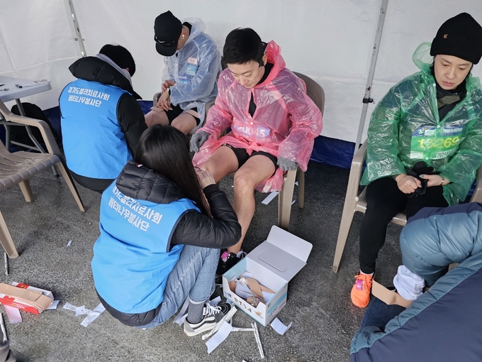 25일 수원종합운동장에서 열린 2024 경기수원국제하프마라톤대회에서 참가자들이 물리치료사에게 테이핑을 받고 있다. (사진=마라톤 특별취재팀)