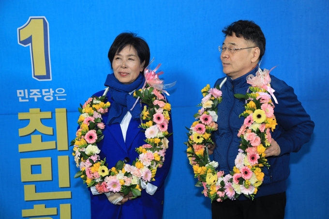 최민희 당선인이 남편 정수웅씨와 함께 지지자들이 건낸 축하 화환을 걸고 기뻐하고 있다.(사진=최 당선자 측 제공)