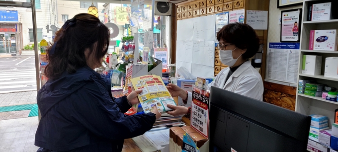 광주시 한 약국에서 감영볌 예방 정보 제재된 약 봉투를 건내받고 있다. (사진=광주시 제공)