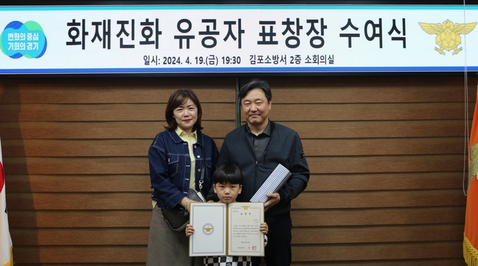 아파트 큰 화재를 예방한 주민 김형권씨가 김포소방서로부터 감사패를 받고 자녀와 함께 기념사진을 찍고 있다. (사진=김포소방서 제공) 