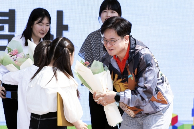 김포시가 지난 4일 102회 어린이날 하루를 앞두고 ‘꿈과 행복으로 통하는 주제로 관내 4개 공원에서 풍성한 행사에 참석한 김병수 시장이 아이들 눈높이에 맞춰 앉아 꽃을 선사하고 있다. (사진=김포시청 제공)
