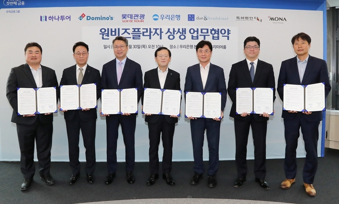 (왼쪽부터) 이대훈 하나투어 상무, 김영훈 도미노피자 사장, 백현 롯데관광 대표이사, 조병규 우리은행장, 오유근 나이스디앤비 대표이사, 김진수 모나용평 부사장, 진희동 특허법인다나 대표 변리사가 협약식 이후 기념사진을 촬영하고 있다. (사진=우리은행 제공)
