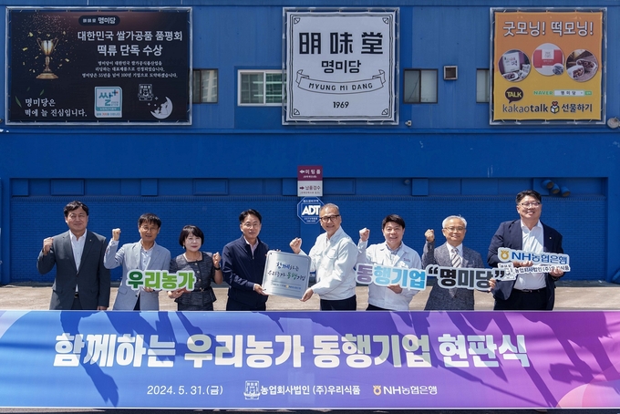 이석용 NH농협은행장(왼쪽 4번째)과 이상준 우리식품 대표이사(왼쪽 5번째)를 비롯한 양사 임직원들이 현판식을 갖고 기념촬영을 하고 있다. (사진=NH농협은행 제공)