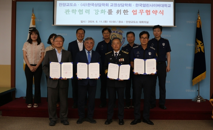 신동윤 안양교도소장(앞줄 오른쪽 두 번째)이 11일 한국상담학회 교정상담학회, 한국열린사이버대학교와 업무협약을 한 뒤 관계자들과 협약서를 들고 기념촬영을 하고 있다. (사진=안양교도소 제공)