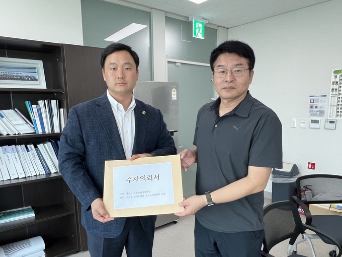 고준호(파주1·왼쪽) 국민의힘 경기도의원과 이종익 경기도 특별사법경찰단 수사총괄팀장이 21일 경기도의회에서 경기도장애인생산품판매시설 대표에 대한 수사의뢰서를 들어 보이고 있다. (사진=경기도의회 제공)