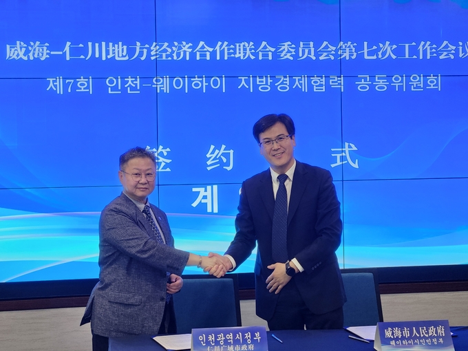 윤현모 인천시 글로벌비즈니스협력단장과 장산둥 웨이하이시 부시장이 '제7회 인천-웨이하이 지방경제협력 공동위원회'에서 비망록을 체결한 뒤 악수하고 있다. ( 사진 = 인천시 제공 )