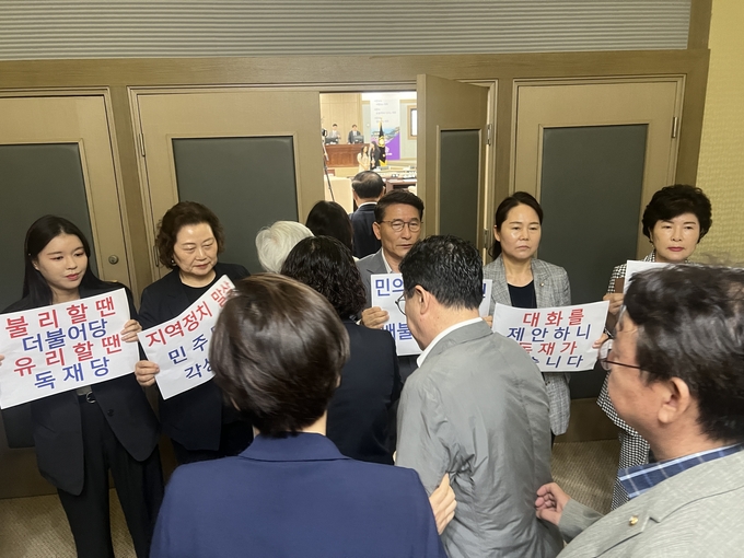 3일 수원시의회 제383회 임시회 제3차 본회의를 앞두고 규탄 시위를 벌이고 있는 국민의힘 의원들 사이로 더불어민주당 의원들이 본회의장에 들어가는 모습. (사진=장진 기자)