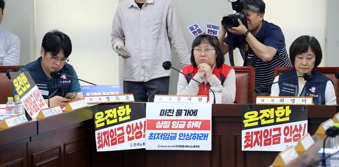 최저임금위원회 근로자 위원들이 지난 9일 오후 정부세종청사 최저임금위원회에서 열린 제9차 전원회의에서 '온전한 최저임금 인상'을 요구하는 피켓을 걸어놓고 있다. (사진=연합뉴스 제공)