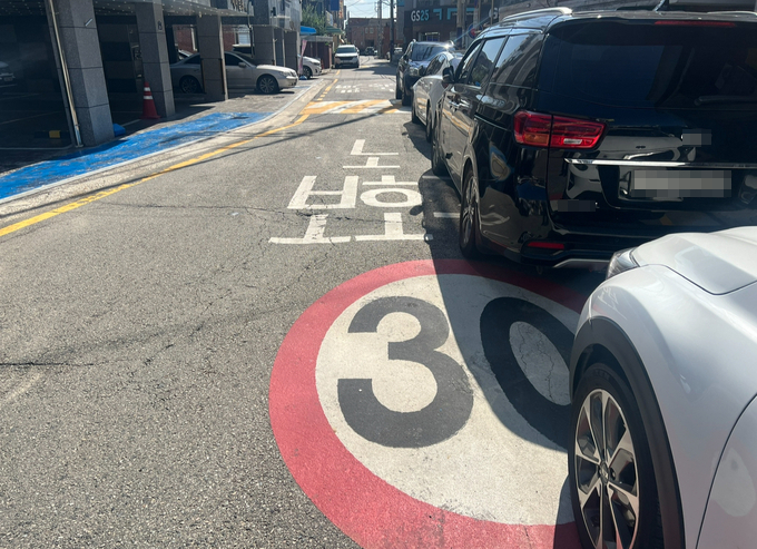 15일 오전 수원시 권선구 고색동 소재 노인 보호구역에 주차된 차량이 노면 표시를 가리고 있는 모습. (사진=장진 기자)