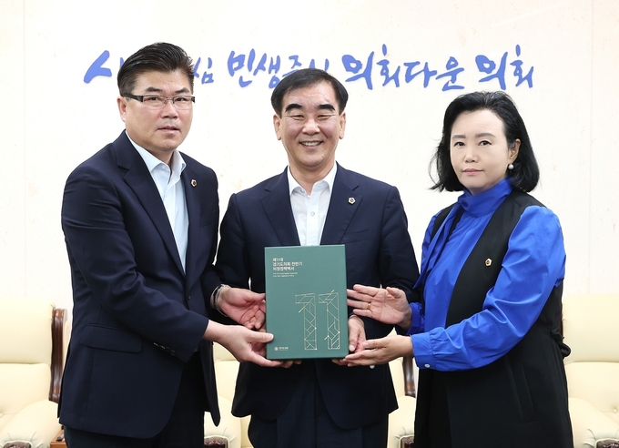 정윤경(민주·군포1)·윤태길(국힘·하남1) 경기도의회 의정정책추진단 공동단장이 염종현 경기도의회 의장에게 ‘제11대 경기도의회 전반기 의정정책백서’를 전달하고 있다. (사진=경기도의회 제공)