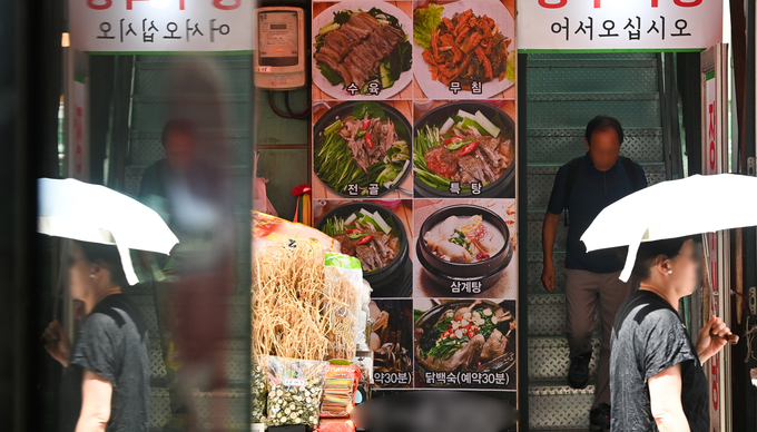 올해 초 '개고기 식용 금지법'이 통과된 이래 첫 중복을 맞은 25일 성남시 모란시장 인근에 위치한 보신탕집에 시민이 나오고 있다. 가게 옆에는 개고기 수육 사진이 걸려있다.