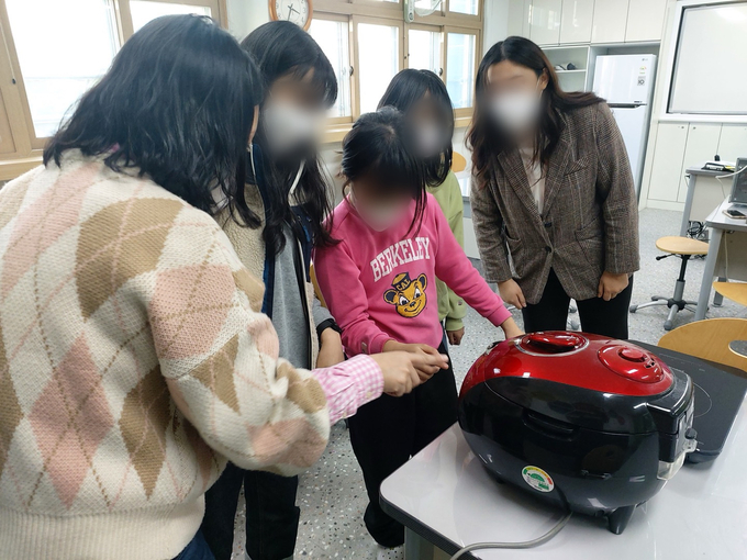 학생들이 일상생활기술훈련 프로그램을 통해 밥솥 사용법을 배우고 있다. (사진=만안초등학교 제공) 