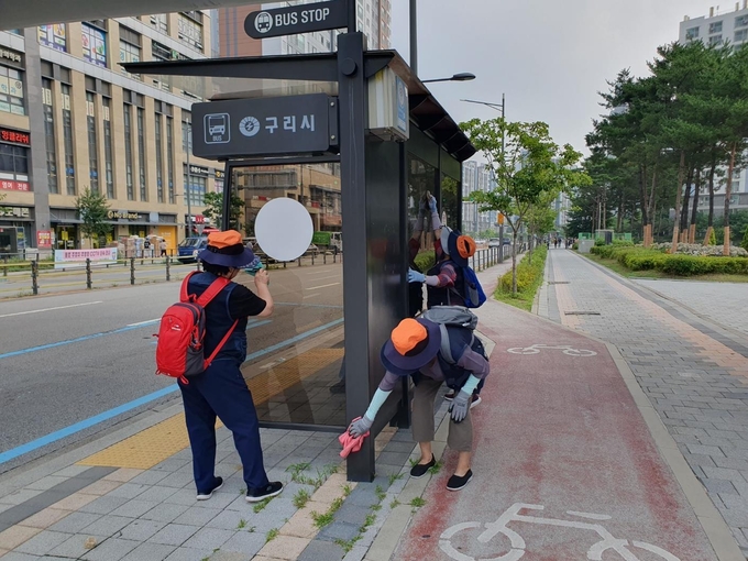 구리실버인력뱅크 공익형 사업인 ‘대중교통지킴이’ 참여 어르신들이 버스정류장의 환경 정화를 돕고 있다. (사진=구리시 제공)