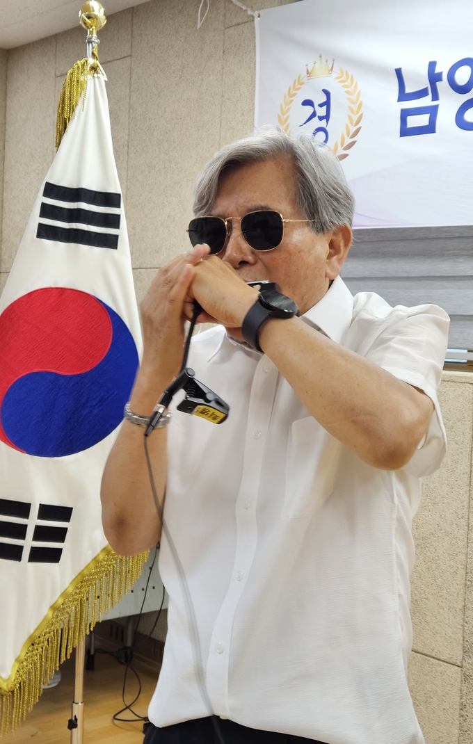 음악가 최병일 씨가 이취임식 식전 행사로 하모니카를 연주하며 분위기를 띄우고 있다.(사진=신소형 기자)