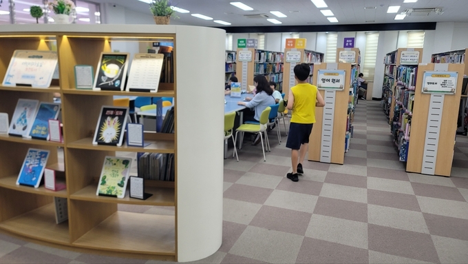책장에서 책을 꺼낸 학생이 자리로 이동하고 있다. ( 사진 = 이연수 기자 )