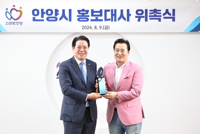 최대호 안양시장(왼쪽)이 9일 탤런트 겸 가수로 활동 중인 김성환에게 홍보대사 위촉패를 전달하고 있다. (사진=안양시 제공)
