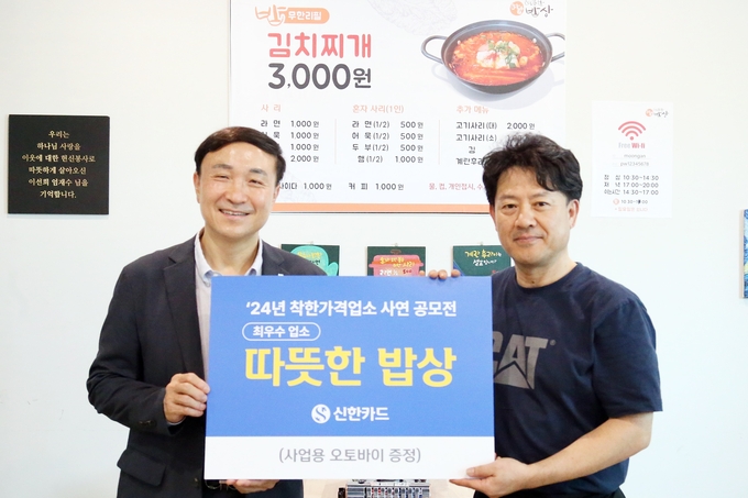 문동권 신한카드 사장(왼쪽)이 최우수 업소로 선정된 서울 은평구 소재 '따뜻한 밥상(연신내점)'을 방문해 사업용 오토바이 경품을 전달한 후 업주와 기념 촬영을 하고 있다. (사진=신한카드 제공)