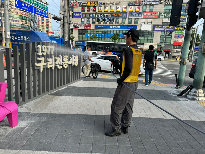 구리시상권활성화재단 관계자가 ‘구리시 클린상권’ 캠페인 청소 작업을 하고 있다. (사진=구리시 제공)