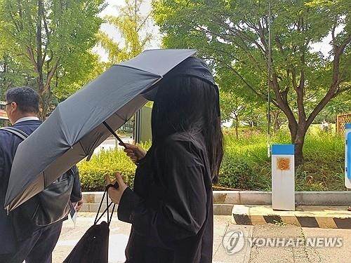 지난달 12일 '탈덕수용소' 운영자가 검은 모자와 우산으로 얼굴을 가린 채 서울중앙지법에서 열린 재판에 출석했다. ( 사진 = 연합뉴스 )