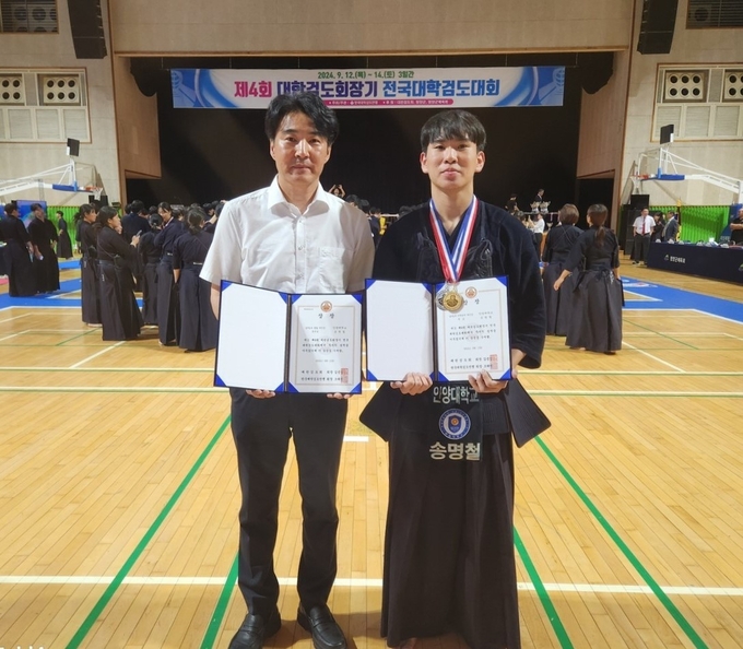 안양대 검도부 송명철 선수(왼쪽)가 저학년부 우승을 차지한 뒤 임종길 검도부 감독과 기념촬영을 하고 있다. (사진=안양대 제공)
