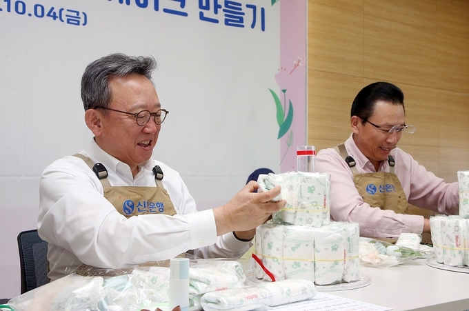 정상혁 신한은행장(왼쪽)이 ‘탄생을 축하해’ 임직원 봉사활동에서 임직원들과 기저귀 케이크를 만들고 있다. (사진=신한은행 제공)