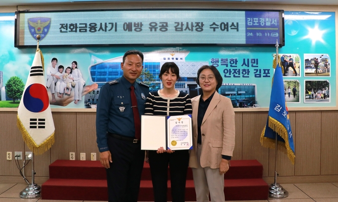 보이스피싱 범죄예방에 기여한 우리은행 직원(중앙)이 김포경찰서장 감사패를 받고 기념사진을 찍고 있다. (사진=김포경찰서 제공)