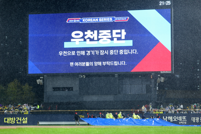 21일 광주 기아챔피언스필드에서 열린 2024 신한 SOL뱅크 KBO 포스트시즌 한국시리즈 1차전 6회초 폭우로 인해 경기장 관계자들이 방수포를 그라운드에 덮고 있는 모습. (사진=연합뉴스)