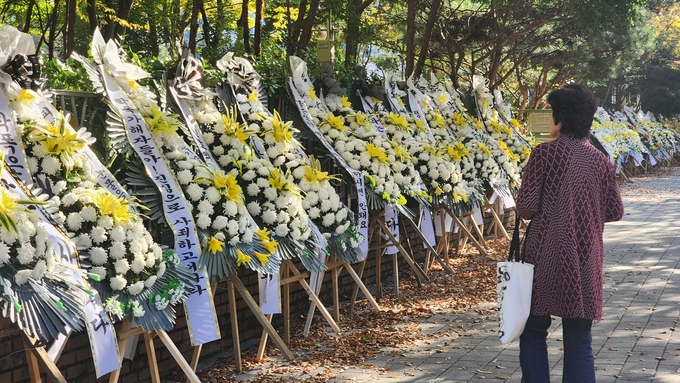  24일 학교폭력이 발생한 성남시 분당구 서현초등학교 앞에 학부모들이 설치한 화환을 인근 주민이 보고 있다. (사진=박진석 기자)