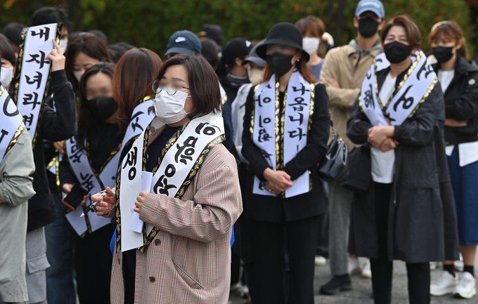 29일 성남시 분당구 서현중학교에 모인 학부모들이 가해 학생을 규탄하는 문구가 적힌 근조화환 리본을 두르고 학교운영위원회 회의 방청을 위해 이동하고 있다. (사진=옥지훈 기자)