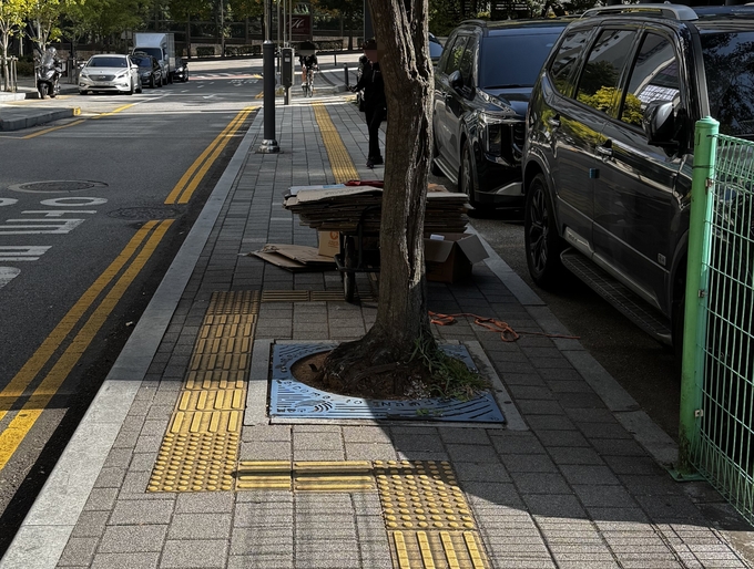 남동대로 799번길 인근 폐지 더미를 올린 손수레가 점자 블록 위 보행을 방해하고 있다. ( 사진 = 유지인 기자 )
