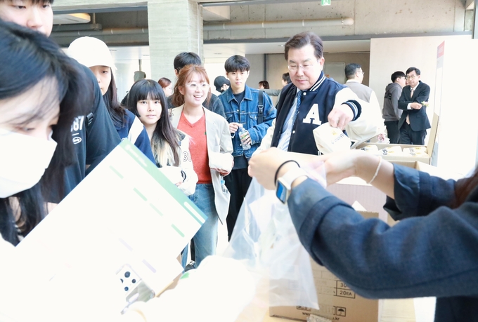 장광수 안양대 총장이 '아리 엑스포' 개막 첫날 학생들에게 간식을 나눠주며 격려하고 있다. (사진=안양대 제공)