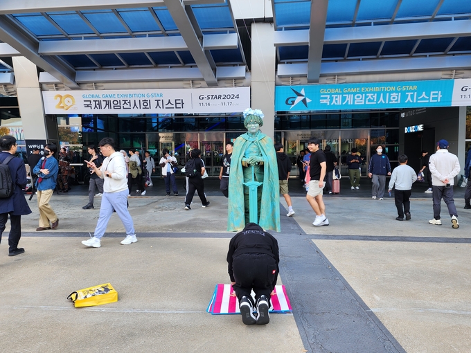 동상으로 분한 코스어를 앞에 두고 한 관람객이 그를 숭배하고 있다. (사진=이효정 기자)