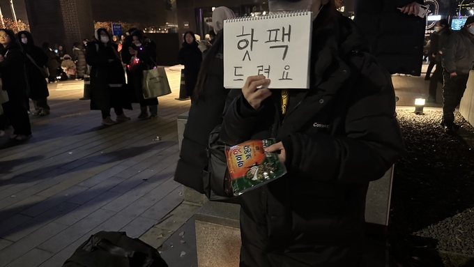 7일 한 시민이 여의도 국회의사당 앞에서 집회에 참여한 시민들에게 핫팩을 나눠주고 있다. (사진=박민정 기자)