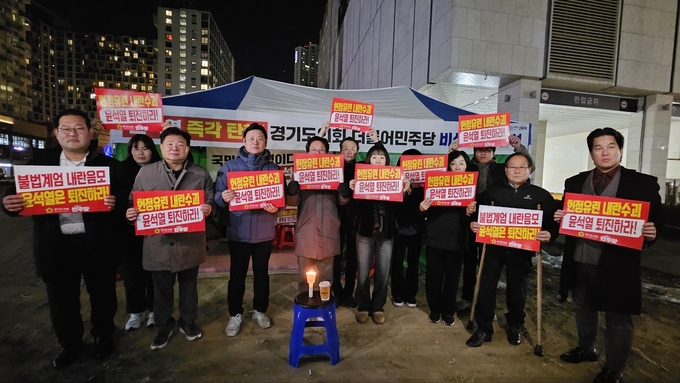 더불어민주당 광역의회의원협의회가 지난 9일 밤 경기도청 인근에서 윤석열 대통령의 퇴진을 촉구하는 내용이 적힌 피켓을 들어 올리고 있다. (사진=경기도의회 제공)
