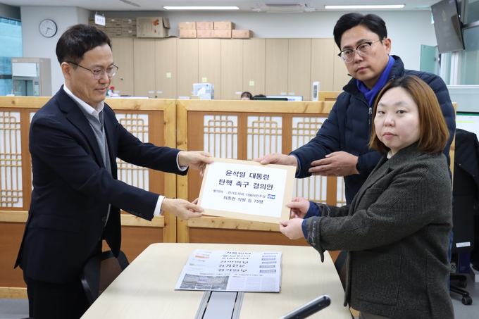 경기도의회 더불어민주당 이용욱(파주3) 총괄수석부대표와 전자영(용인4) 수석대변인이 12일 경기도의회에서 ‘윤석열 대통령 탄핵 촉구 결의안’을 들고 있다. (사진=경기도의회 제공)