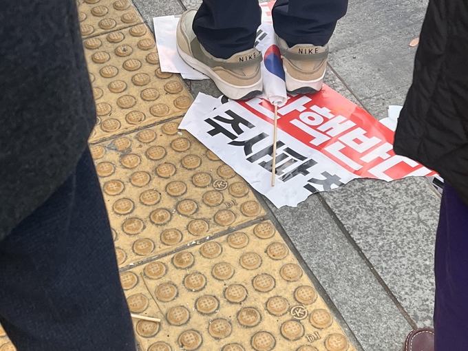 14일 광화문 일대에서 집회 손팻말이 찢긴 채 태극기와 함께 바닥에 버려져있다. (사진=장진 기자)