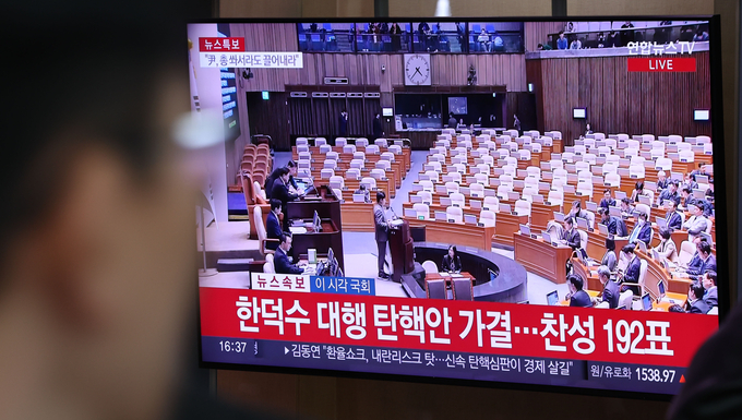27일 서울역에서 시민들이 한덕수 대통령 권한대행 국무총리에 대한 탄핵소추안 가결 생방송을 지켜보고 있다. (사진=연합뉴스)