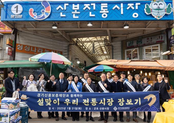 21일 군포시 산본시장에서 열린 ‘전통시장 활성화를 위한 설맞이 장보기 행사’에서 시석중 경기신보 이사장, 정윤경(민주·군포1) 도의회 부의장 등 참석자들이 기념촬영을 하고 있다. (사진=경기신보 제공)